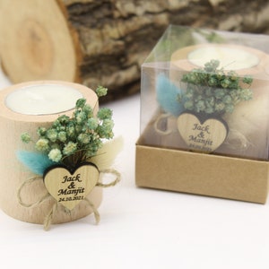 May include: A small wooden candle holder with a white candle inside. The holder is decorated with dried flowers and a heart-shaped wooden tag with the text "Jack & Manjit 24.10.2021".