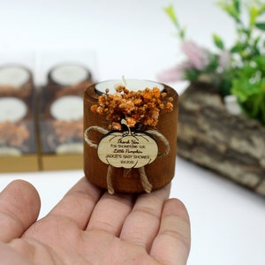 May include: A small wooden candle holder with a tea light candle inside. The holder is decorated with dried flowers and a small wooden tag that says "Thank You for showering our Little Pumpkin, Jack's Baby Shower, Oct 2022".