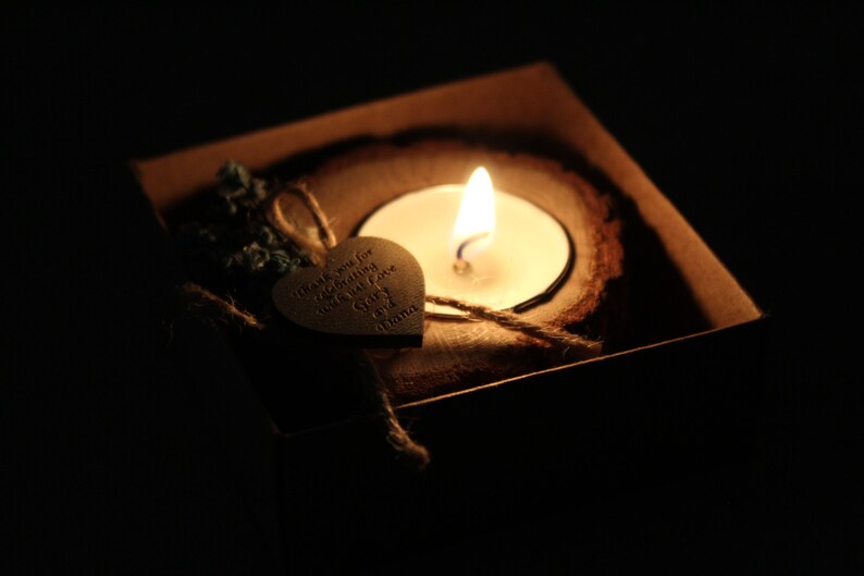 Pu&ograve; includere: Un cuore di legno con il testo "Grazie per aver celebrato il nostro giorno speciale" e una piccola candela in un portacandele di legno.