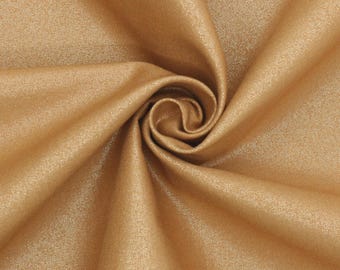 May include: Close-up of a swirl of golden-colored fabric. The material has a subtle sheen, with visible folds and textures. The fabric appears to be smooth and flowing, with a slight shimmer. The overall impression is of luxury and elegance.