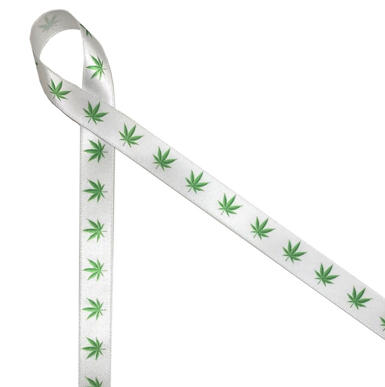 Puede incluir: Cinta de sat&eacute;n blanca con un patr&oacute;n repetido de hojas verdes de marihuana.