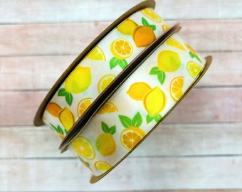 May include: Two rolls of white satin ribbon with a lemon print. The ribbon is yellow and green with a white background.