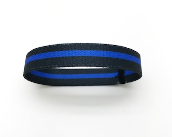 May include: A black and blue woven wristband with a thin blue stripe.