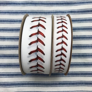 May include: Two spools of white ribbon with a baseball stitch design. The stitching is red.