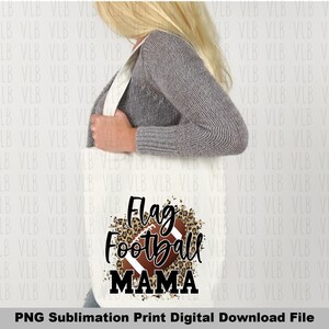 May include: A white tote bag with a brown and black leopard print design and a football graphic. The text "Flag Football Mama" is printed in black on the bag.