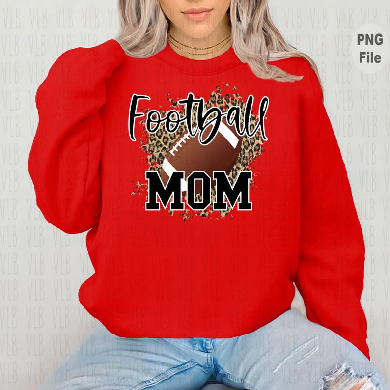 May include: Red sweatshirt with a football and leopard print design. The text "Football Mom" is printed on the sweatshirt.