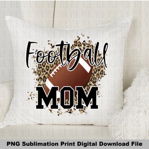May include: A white pillow with a brown football and leopard print design. The text "Football Mom" is printed in black.