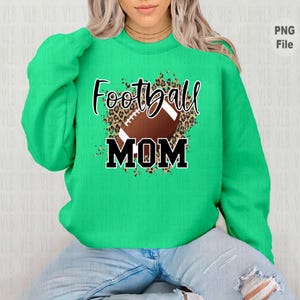 May include: Green sweatshirt with a black and brown football graphic and the text "Football Mom" in black.