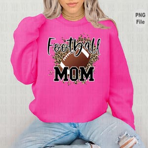 May include: Pink sweatshirt with a brown and black leopard print design featuring a football and the text "Football Mom".