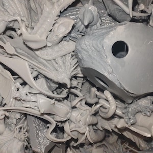 May include: A pile of unassembled, light gray plastic model kit parts. The components include dragon wings, figures, and architectural elements. The parts are intricately detailed and appear to be from a fantasy or sci-fi themed model kit.