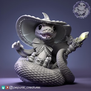 May include: A detailed sculpture of a snake in a witch's hat and cape, holding a staff with a glowing crystal. The snake is coiled, with intricate scales and a bow tie. A small bird emblem is in the background. The artist's social media handle is visible.