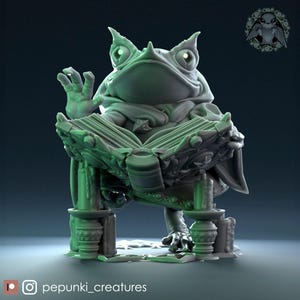 May include: A detailed, green-toned sculpture of a frog-like creature seated and reading a book. The frog is wearing a hooded robe and has its hand raised. The book rests on a decorative stand. The sculpture has a fantasy theme.
