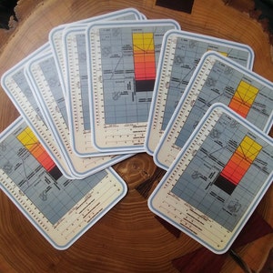 May include: A collection of rectangular coasters with a vintage map design. The coasters feature a light blue border and a color gradient from yellow to red. The map includes grid lines and text, creating a retro aesthetic.