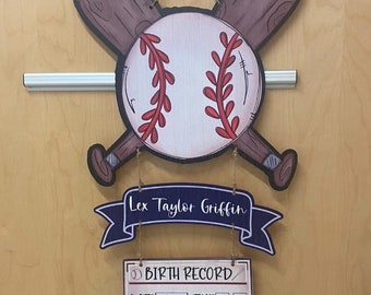 Può includere: Un cartello di annuncio di nascita in legno a tema baseball con uno striscione blu che recita "Lex Taylor Griffin". Il cartello include una palla da baseball, due mazze incrociate e un record di nascita a forma di home plate con la data, l'ora, la lunghezza e il peso del bambino. Il bambino è nato il 10/19/22 alle 10:20, misurava 21 pollici di lunghezza e pesava 8 libbre 5 once.