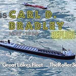 Peut inclure: Un modèle du SS Carl D. Bradley, un cargo des Grands Lacs, flotte dans une eau bleue. Le navire est noir avec une superstructure blanche et une plaque de réplique jaune qui indique "SS Carl D. Bradley 1927-1958 Réplique". Le texte "Great Lakes Fleet TheRoller3d" est également visible sur l'image.