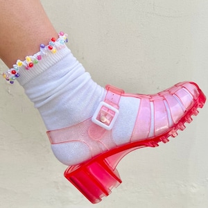 May include: Pink jelly platform sandals with a buckle closure. The sandals are clear and have a chunky heel.