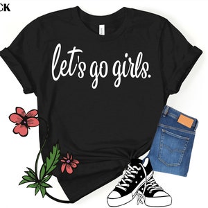 May include: Black t-shirt with white text that reads "Let's go girls."