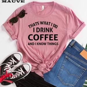 May include: A pink t-shirt with the text "That's what I do I drink coffee and I know things" printed in black.