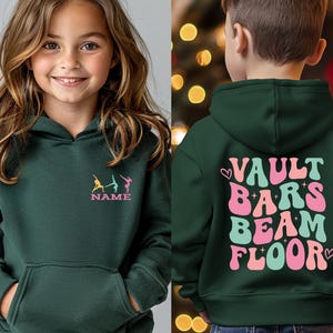 Puede incluir: Sudadera con capucha verde oscuro con bolsillo delantero y capucha. La parte delantera presenta un dise&ntilde;o de gimnasia y la palabra "NAME". La parte trasera de la sudadera dice "VAULT BARS BEAM FLOOR" en letras rosas, verdes y blancas.