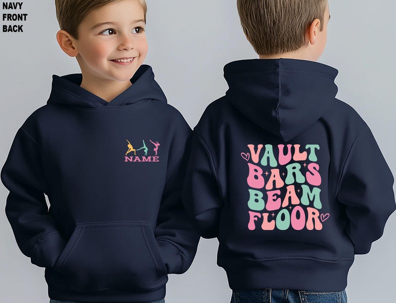 Puede incluir: Sudadera con capucha azul marino. La parte delantera muestra figuras de gimnastas en amarillo, turquesa y rosa, con la palabra "NAME" debajo. La parte trasera tiene las palabras "VAULT BARS BEAM FLOOR" en rosa y turquesa, con corazones.