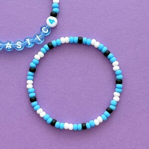 May include: Two beaded bracelets, one with the word "ASTIC" and the number "4" on it, and the other with alternating blue, white and black beads.
