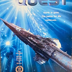 Op de afbeelding: Een VHS-cassettehoes voor de film Star Quest. De hoes toont een ruimteschip in de ruimte met een blauwe en witte achtergrond. De tekst op de hoes luidt "Star Quest" en "De aarde is weg. De strijd om te overleven gaat door..." De hoes bevat ook een Golden Scroll Award-logo en de namen van de acteurs: Steven Bauer, Emma Samms, Alan Rachins en Brenda Bakke.