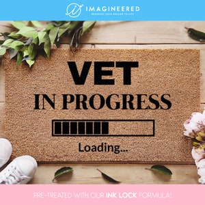 May include: A brown doormat with the text "VET IN PROGRESS" and a loading bar graphic. The text "Loading..." is below the bar. The doormat is pre-treated with an ink lock formula.