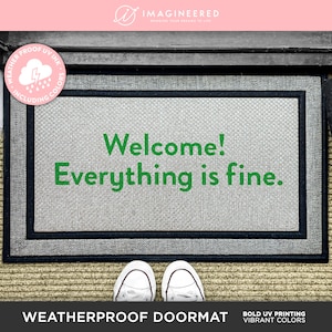 May include: A gray doormat with black trim and the text "Welcome! Everything is fine." printed in green. The doormat is weatherproof and has UV ink.