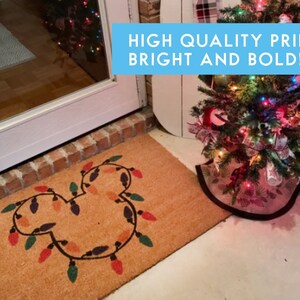 May include: A brown coir doormat with a Mickey Mouse silhouette made of colourful Christmas lights. The text "HIGH QUALITY PRINT! BRIGHT AND BOLD!" is displayed in a blue box above the doormat.