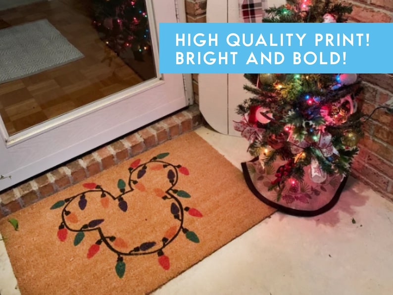 May include: A brown coir doormat with a Mickey Mouse silhouette made of colourful Christmas lights. The text "HIGH QUALITY PRINT! BRIGHT AND BOLD!" is displayed in a blue box above the doormat.