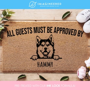 May include: A brown doormat with the text "ALL GUESTS MUST BE APPROVED BY" and a black silhouette of a husky dog peeking over the top. The dog's name, "HAMMY", is written below the dog. The doormat is pre-treated with an ink lock formula.