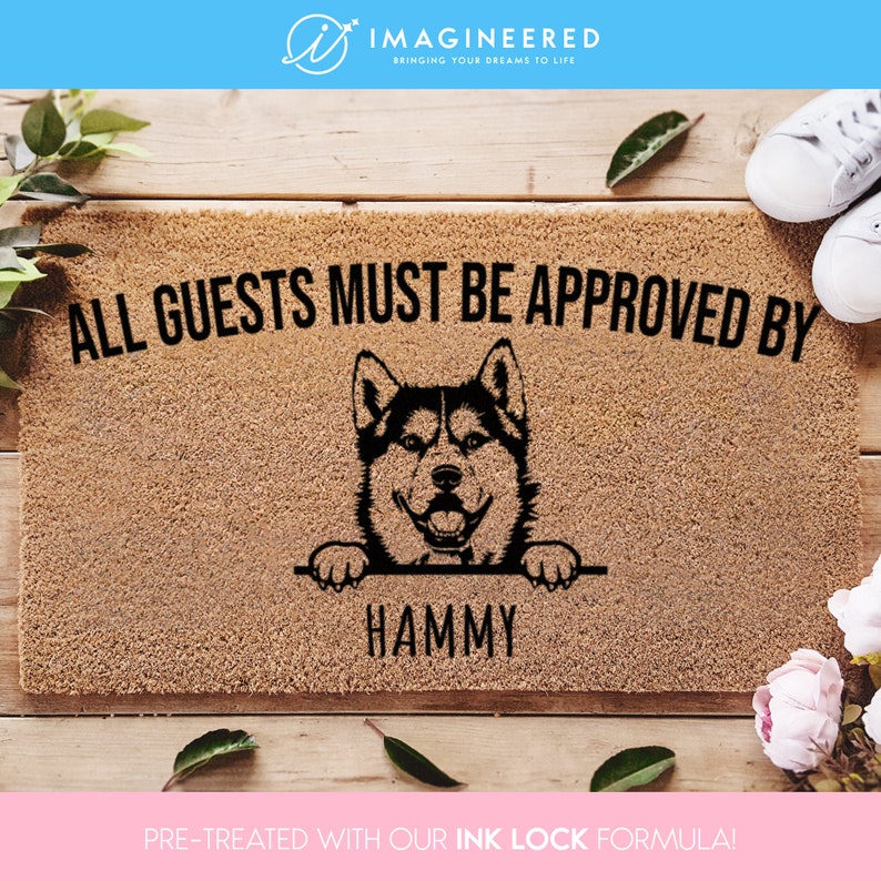 May include: A brown doormat with the text "ALL GUESTS MUST BE APPROVED BY" and a black silhouette of a husky dog peeking over the top. The dog's name, "HAMMY", is written below the dog. The doormat is pre-treated with an ink lock formula.