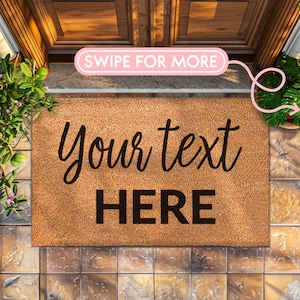 May include: A rectangular doormat made of natural coir fiber. The mat features the words "Your text HERE" in black script and block letters. A pink banner with the words "SWIPE FOR MORE" is in the upper center. The mat is placed in front of a wooden door.