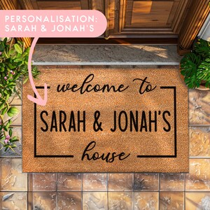 Puede incluir: Una alfombra de coco marrón con el texto "welcome to SARAH & JONAH'S house" en letras negras.