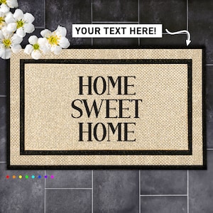 May include: A beige doormat with black trim and the text "HOME SWEET HOME" in black lettering.