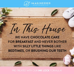 May include: A brown doormat with the text "In This House We Have Chocolate Cake For Breakfast And Never Bother With Silly Little Things Like Bedtimes, Or Brushing Our Teeth" printed in black. The doormat is pre-treated with an ink lock formula.