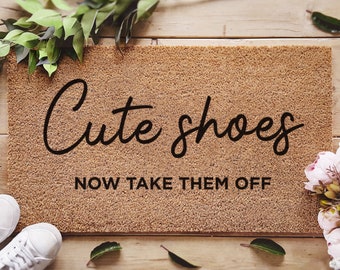 May include: A brown coir doormat with the text "Cute shoes NOW TAKE THEM OFF" in black lettering. The doormat is pre-treated with an ink lock formula.