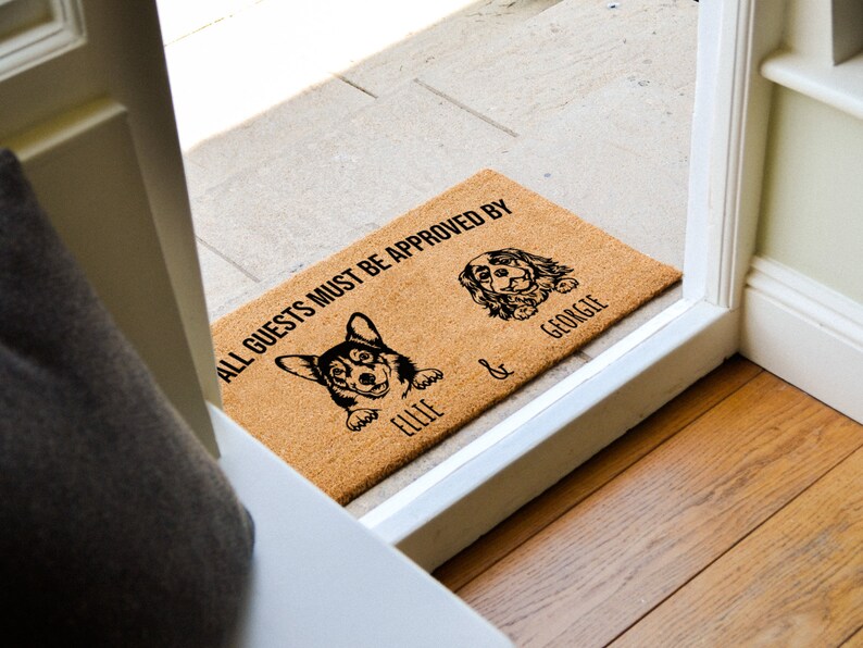 May include: A brown coir doormat with the text "ALL GUESTS MUST BE APPROVED BY" and two dog silhouettes with the names "Ellie" and "George" underneath.