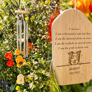 May include: A wooden memorial wind chime with a poem engraved on it. The poem reads: "I am here. I am a thousand winds that blow. I am the diamond glints on snow. I am the sunlight on ripened grain. I am the gentle autumn rain." The chime also features a dog silhouette and the text "Juniper 2012-2023".
