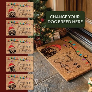 Op de afbeelding: Een bruine kokosmat met de tekst "Merry Christmas!" en een string met gekleurde lampjes. Een hond met een kerstmanmuts bevindt zich in de hoek van de mat. De tekst "CHANGE YOUR DOG BREED HERE" staat in een groene doos boven de mat.