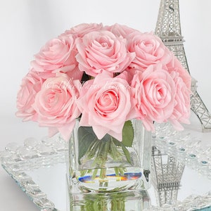 May include: A bouquet of pink silk roses in a clear glass cube vase, sitting on a mirrored tray with a silver Eiffel Tower in the background.