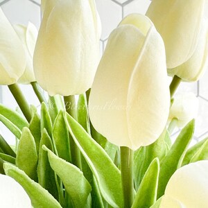May include: A bouquet of cream-colored artificial tulips with green stems and leaves.