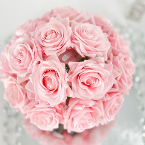 May include: A bouquet of pink roses arranged in a circular shape. The roses are tightly packed together, creating a full and lush appearance.