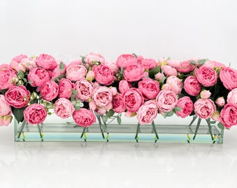 Puede incluir: Un jarrón de vidrio lleno de un gran arreglo de peonías artificiales de color rosa.