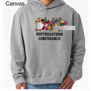 May include: A gray hooded sweatshirt with a front pocket and a drawstring hood. The sweatshirt features a colorful graphic of various cartoon characters and the text "SOUTHEASTERN CONFERENCE". The brand name "Bella Canvas" is printed on the upper left.