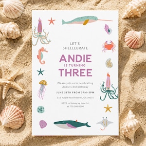 May include: A white rectangular birthday invitation card featuring colorful illustrations of sea creatures including a narwhal, crab, jellyfish, and whale. The text reads: LET'S SHELLEBRATE ANDIE IS TURNING THREE, with event details for June 28th at 3PM.