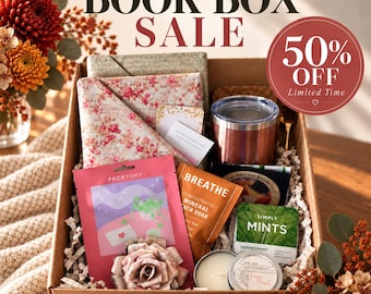May include: A cardboard gift box containing a floral fabric wrap, a metallic tumbler, a pink Facetory sheet mask, a Breathe mineral bath soak packet, a Simply Mints peppermint tin, a candle, and a paper flower. Text reads BOOK BOX SALE 50% OFF.