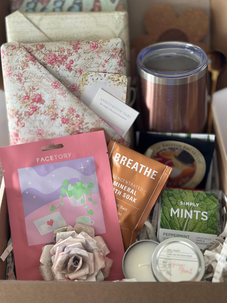 Mother’s Day blind date with a book box featuring wrapped floral book, candle, bath soak, face mask, tea, mints, and insulated tumbler arranged in a cozy self care gift set. Aesthetic book lover gift for mom, mystery book box idea, reader care package, and relaxing reading night essentials. Perfect book club gift, personalized book bundle, and thoughtful self care box designed for women who enjoy cozy reading experiences. Curated Book Box, Book Mail