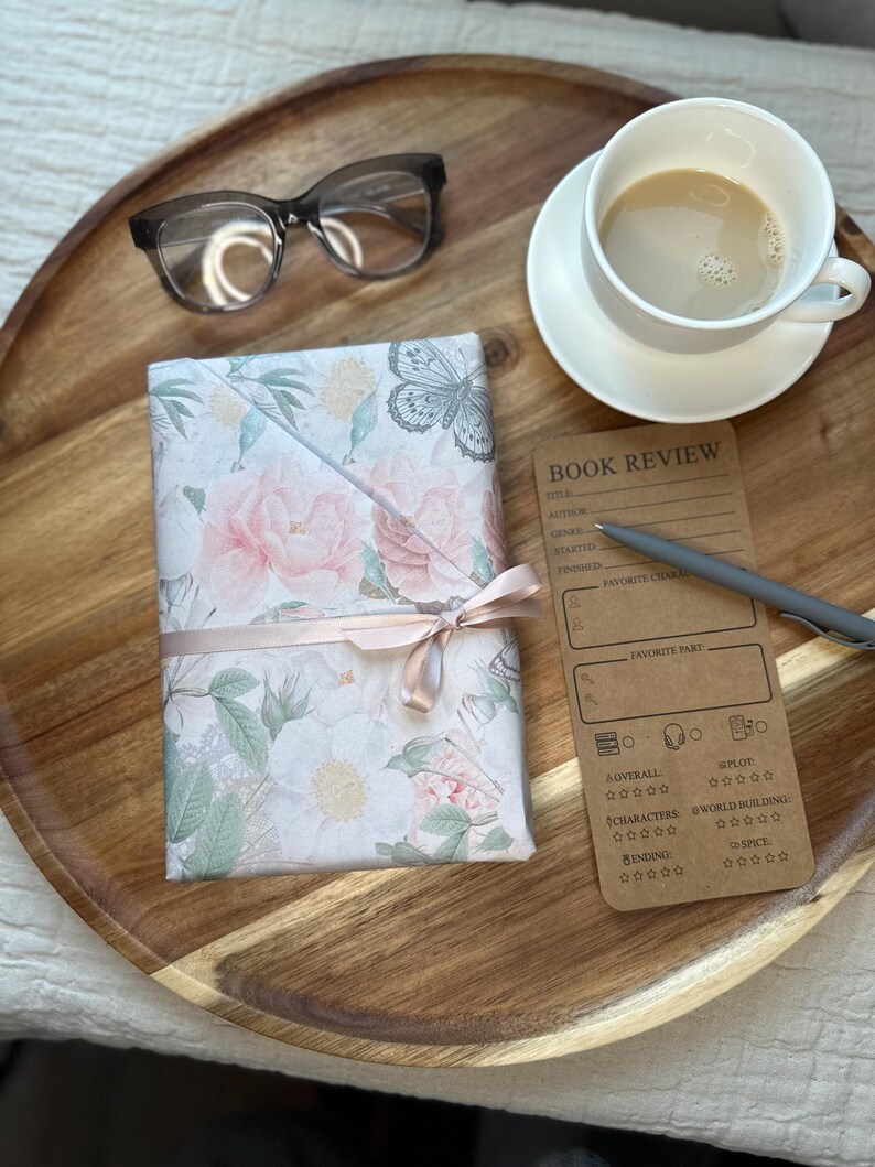 Cozy reading setup featuring wrapped floral book, coffee cup, glasses, and book review card on wooden tray. Mother’s Day book lover gift idea and blind date with a book concept showing relaxing reading moment. Perfect reader gift set, cozy self care experience, and aesthetic bookish gift for mom, book club members, and women who enjoy quiet reading time.