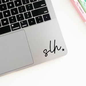 May include: A silver laptop computer with a black sticker that says "sth" with a star next to it.